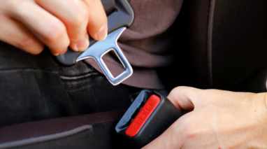 Man fastening his seat belt on the inside of his car