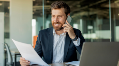 Man in office talkin on the phone and looking at documents