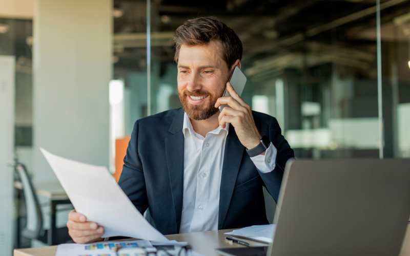 Man in office talkin on the phone and looking at documents