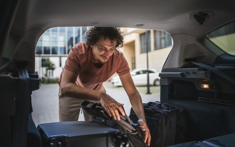 Man loading luggage in car trunk