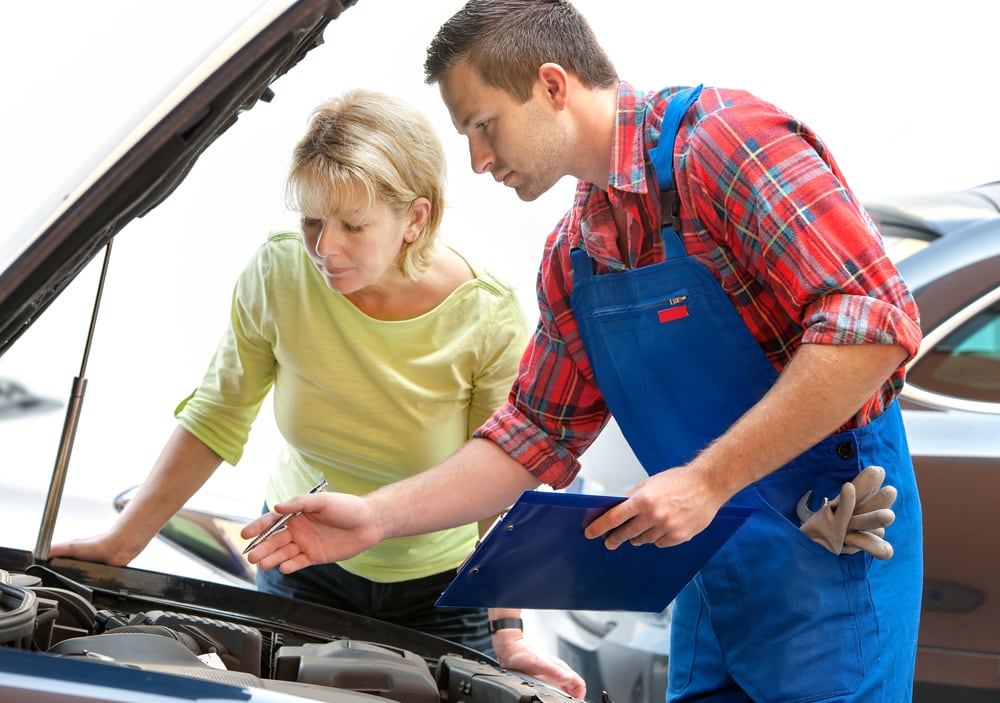 Woman examines car engine with her mechanic