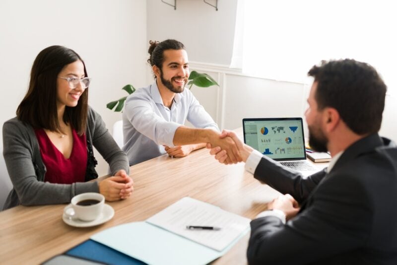 Insurance agent sitting behind desk talks to young couple about high-risk insurance - selling insurance in niche markets