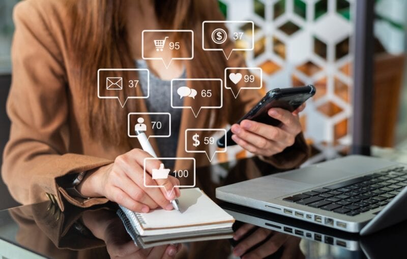 Young woman visible from neck down working on marketing materials.