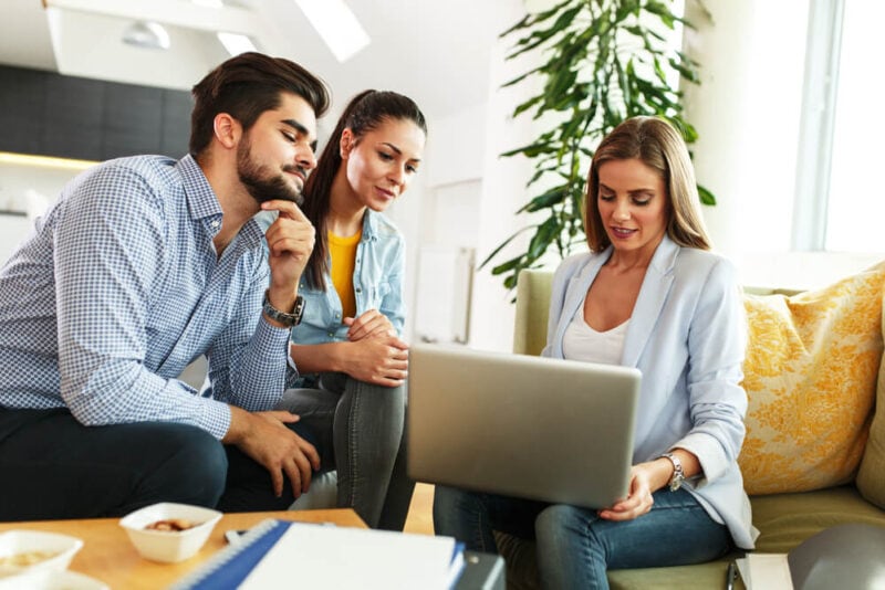 A female insurance agent works on a laptop with a couple buying insurance.