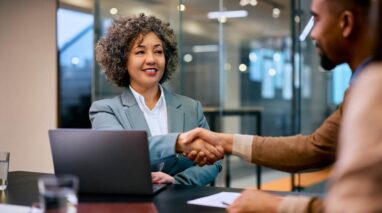 African American insurance agent shakes hands with male customer.