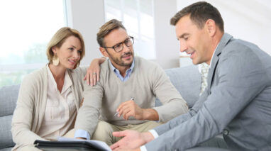 Mature couple speaking with agent who is showing them an ipad.