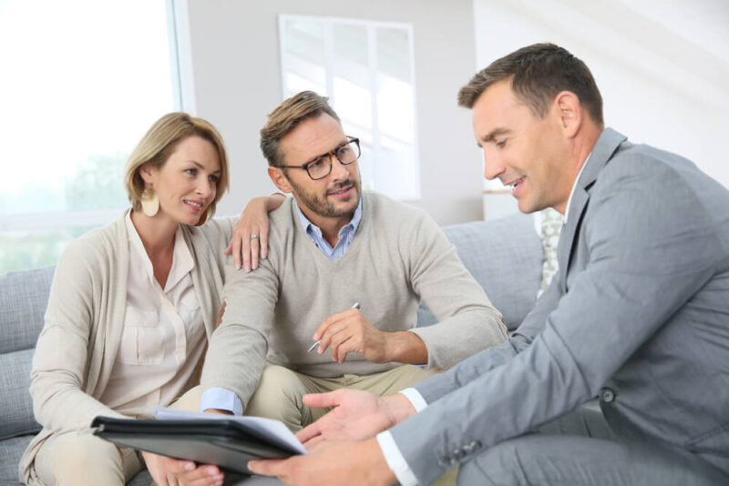 Mature couple speaking with agent who is showing them an ipad.